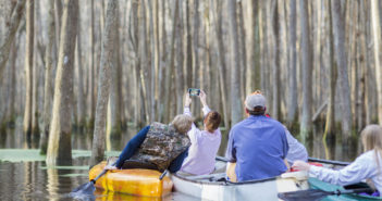 Family taking cell phone photographs in canoes on river