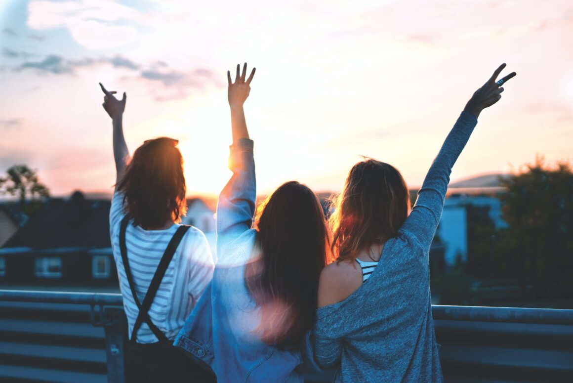 A group of women traveling together watch the sunset.