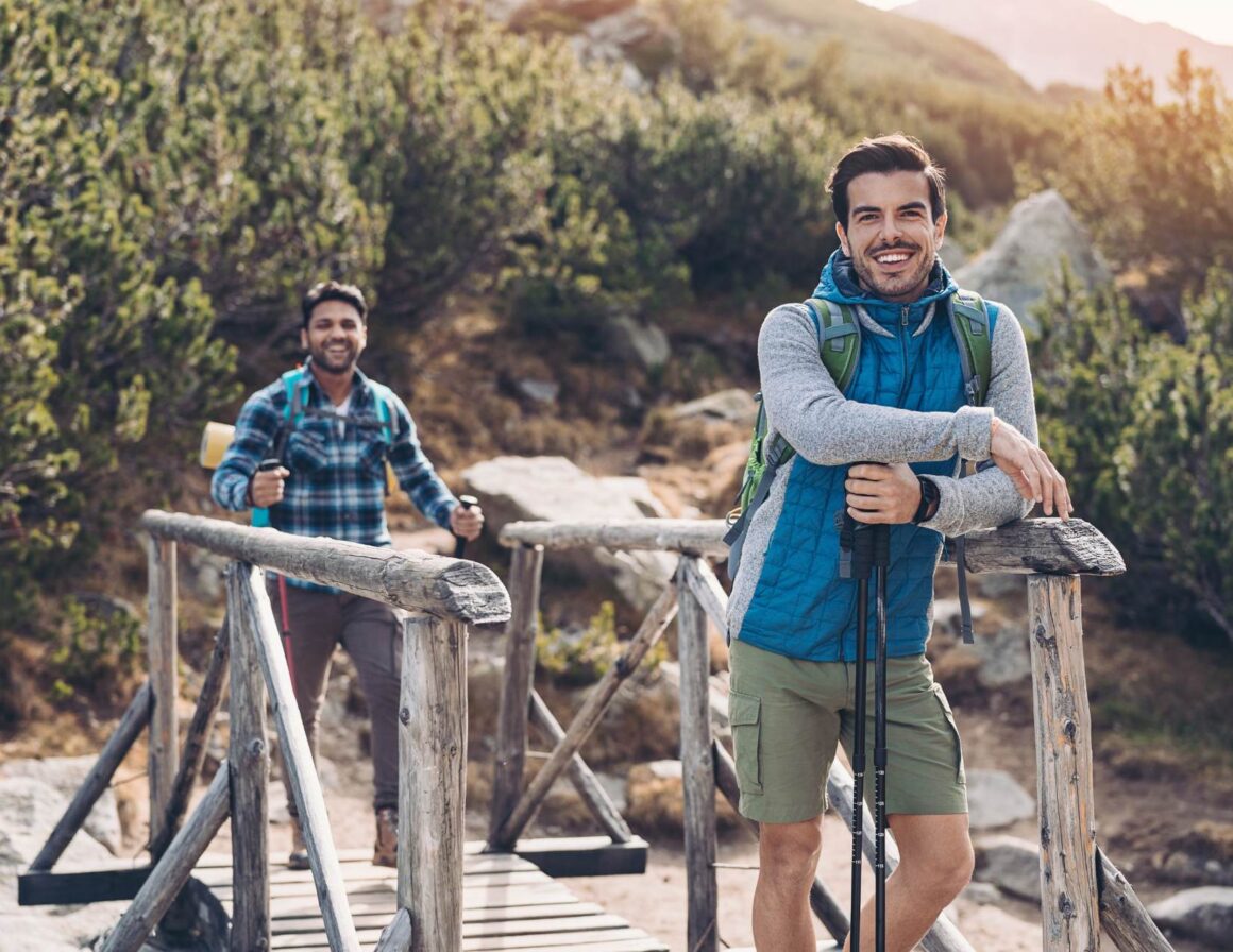 Two men hiking a mountain trail while on an eco-conscious vacation.